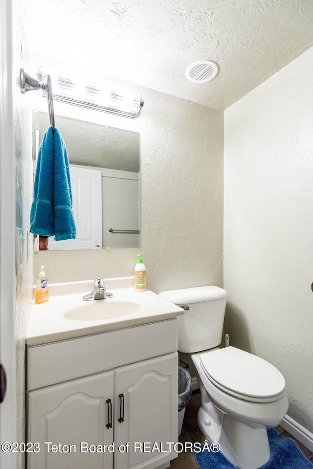 17 C B Ln, Pinedale, WY 82941 - half bathroom featuring a textured wall, vanity, toilet, and a textured ceiling