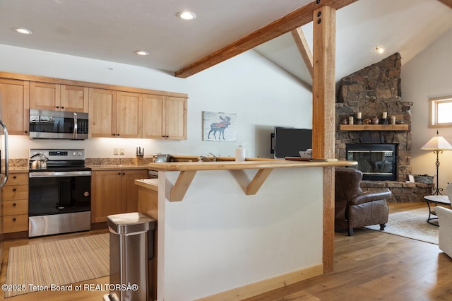 3723 W Michael Dr Unit 13, Teton Village, WY 83025 - kitchen featuring light wood-style flooring, open floor plan, vaulted ceiling with beams, light brown cabinets, and appliances with stainless steel finishes