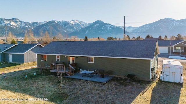 rear view of house with a lawn, a deck with mountain view, and a storage unit