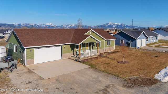 ranch-style home with concrete driveway, a porch, roof with shingles, a mountain view, and a garage