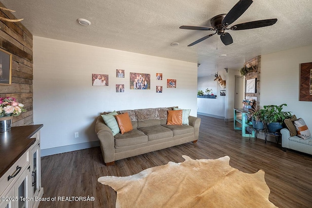 living area featuring baseboards, a ceiling fan, wood finished floors, and a textured ceiling