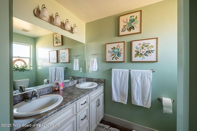 full bathroom with visible vents, a sink, double vanity, and toilet