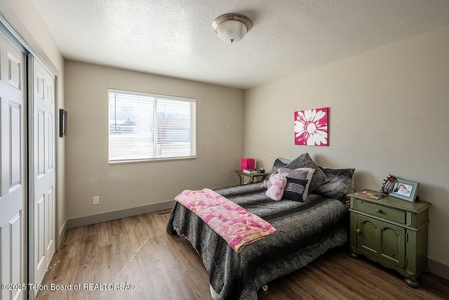 bedroom featuring baseboards, wood finished floors, a textured ceiling, and a closet