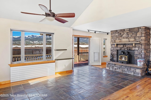 708 Palisades Ln, Alpine, WY 83128 - unfurnished living room with a wood stove, track lighting, baseboards, and a wealth of natural light