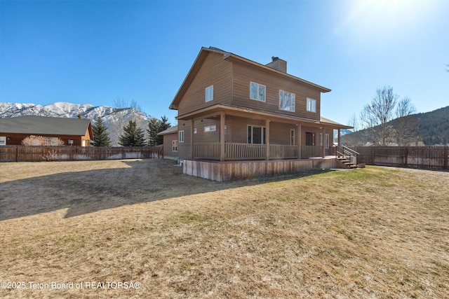 708 Palisades Ln, Alpine, WY 83128 - rear view of property featuring a mountain view, a porch, a fenced backyard, and a chimney