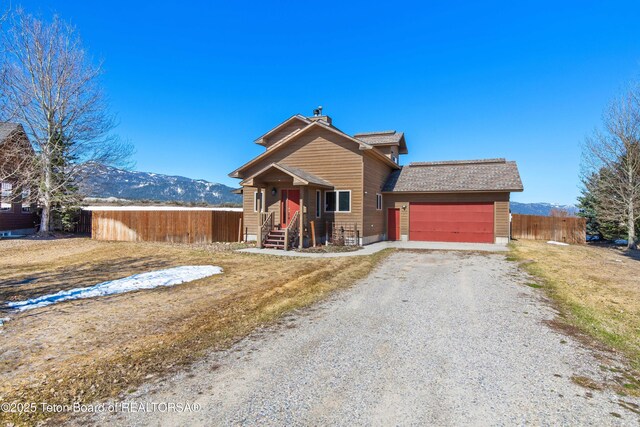 708 Palisades Ln, Alpine, WY 83128 - view of front of property with a mountain view, an attached garage, fence, and gravel driveway