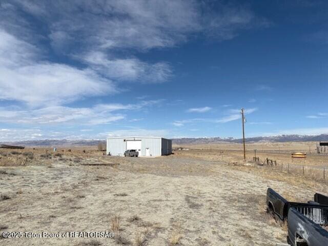 view of yard featuring an outbuilding, a garage, and a rural view