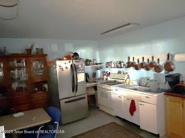 kitchen with light countertops, freestanding refrigerator, and white range with gas cooktop