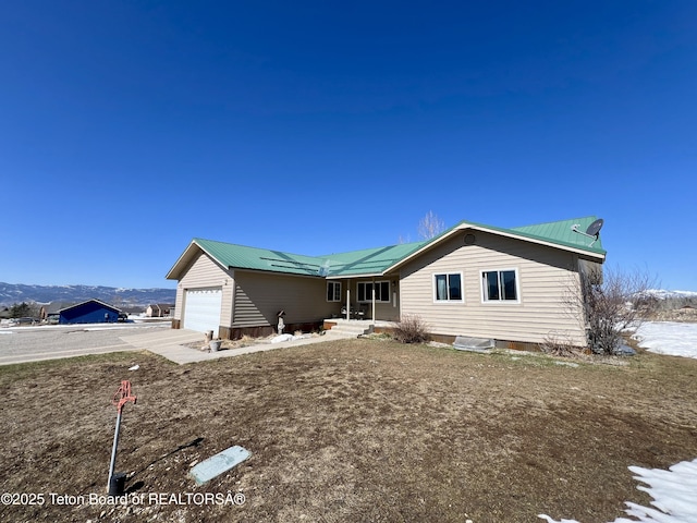 exterior space with a mountain view, an attached garage, metal roof, and concrete driveway