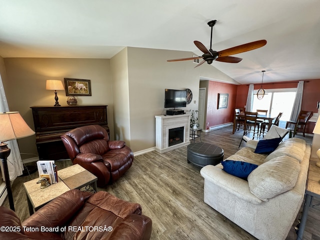 living area with baseboards, a fireplace, a ceiling fan, lofted ceiling, and wood finished floors