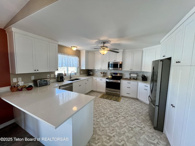 kitchen with a sink, light countertops, a ceiling fan, a peninsula, and stainless steel appliances