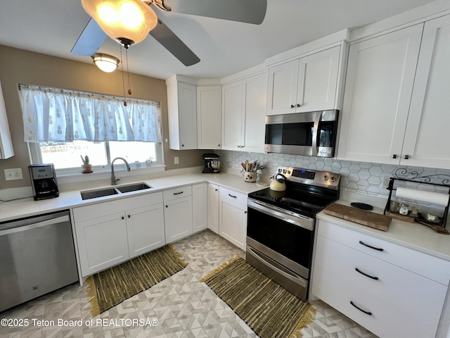 kitchen with tasteful backsplash, a ceiling fan, white cabinets, appliances with stainless steel finishes, and a sink