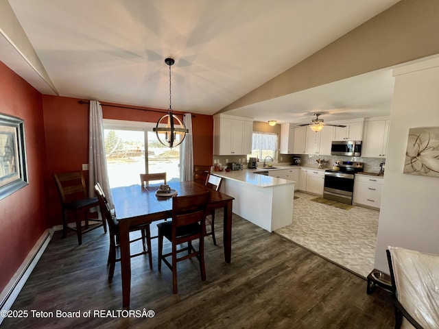 dining space featuring baseboard heating, dark wood-style flooring, a notable chandelier, and lofted ceiling