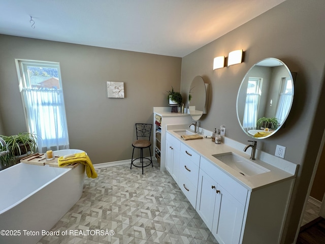 full bathroom featuring a freestanding tub, double vanity, a sink, and baseboards