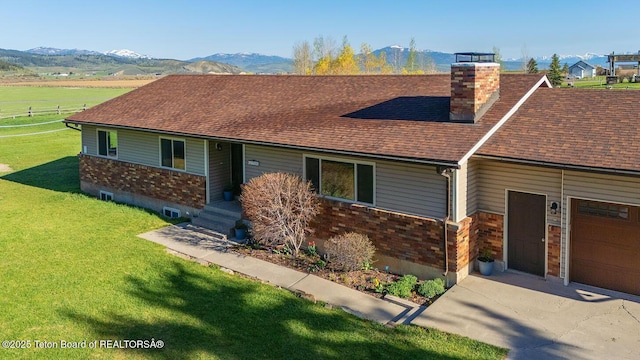 102295 US Highway 89, Thayne, WY 83127 - view of front of property featuring a chimney, roof with shingles, brick siding, a front lawn, and a mountain view