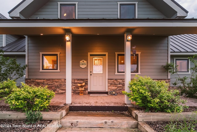 property entrance featuring a porch and stone siding