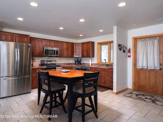 kitchen featuring a sink, stainless steel appliances, backsplash, baseboards, and recessed lighting