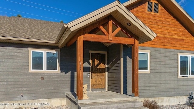 entrance to property featuring roof with shingles