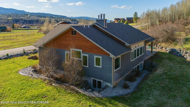 view of home's exterior with a mountain view, a chimney, and a shingled roof