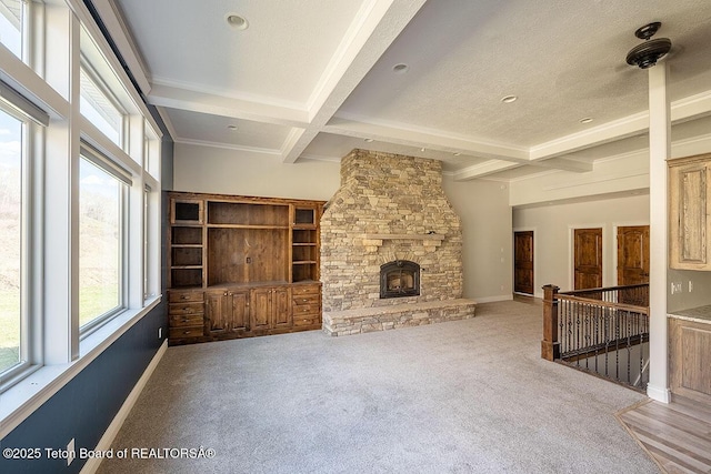 unfurnished living room with beamed ceiling, carpet, coffered ceiling, baseboards, and a stone fireplace