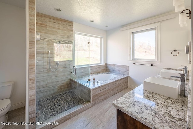 bathroom with toilet, a stall shower, a bath, double vanity, and a textured ceiling