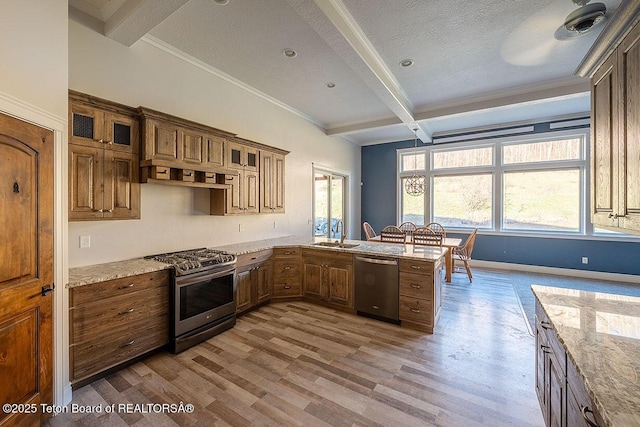 kitchen featuring appliances with stainless steel finishes, beam ceiling, light wood finished floors, a peninsula, and a sink