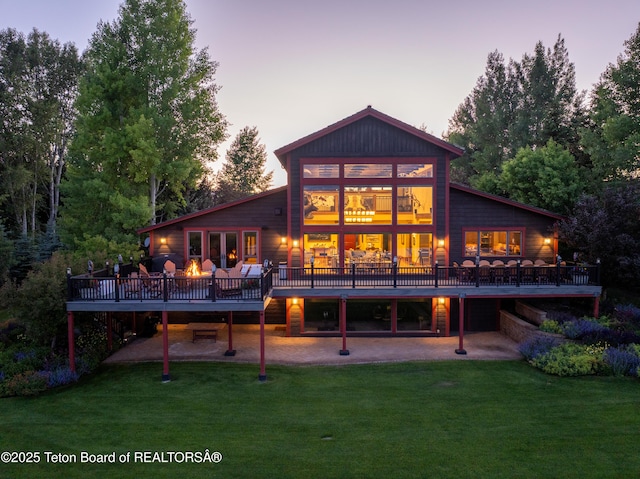 4053 S Adams Rd, Driggs, ID 83422 - back of property at dusk with a deck, a yard, and a patio area