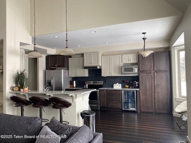 120 Baywood Dr, Driggs, ID 83422 - kitchen featuring wine cooler, dark brown cabinetry, a breakfast bar area, under cabinet range hood, and stainless steel appliances