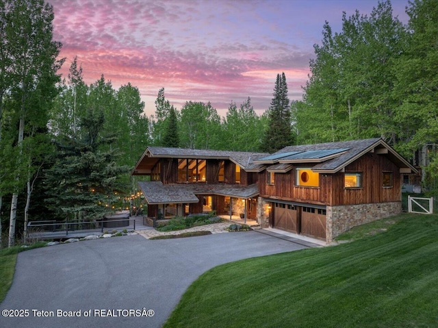 3375 W Killdeer Rd, Jackson, WY 83001 - view of front of house with covered porch, driveway, stone siding, a front yard, and a garage