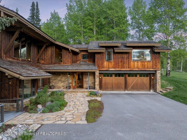 3375 W Killdeer Rd, Jackson, WY 83001 - view of front facade with a garage, asphalt driveway, stone siding, and a porch