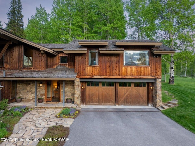 3375 W Killdeer Rd, Jackson, WY 83001 - view of front facade featuring a garage, driveway, a front lawn, stone siding, and a porch