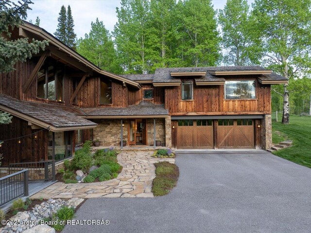 3375 W Killdeer Rd, Jackson, WY 83001 - view of front facade with an attached garage, driveway, covered porch, and stone siding