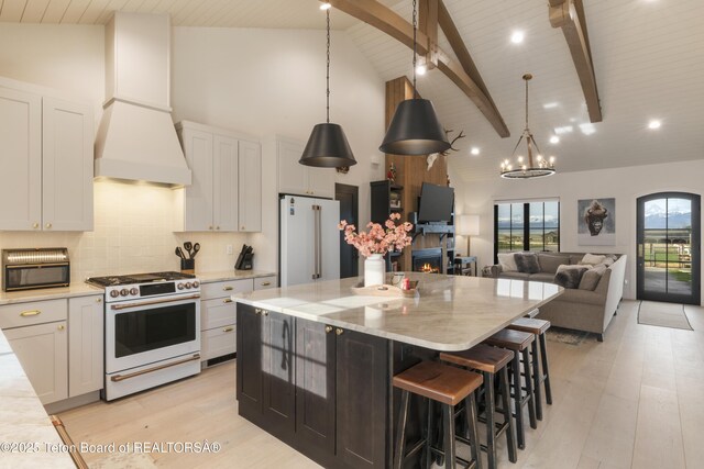 1070 Horseshoe Ln, Driggs, ID 83422 - kitchen featuring white gas range, high end refrigerator, custom range hood, light wood finished floors, and beamed ceiling