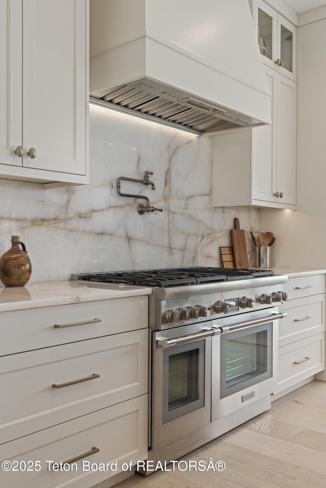 1070 Horseshoe Ln, Driggs, ID 83422 - kitchen featuring range with two ovens, custom range hood, tasteful backsplash, and white cabinets