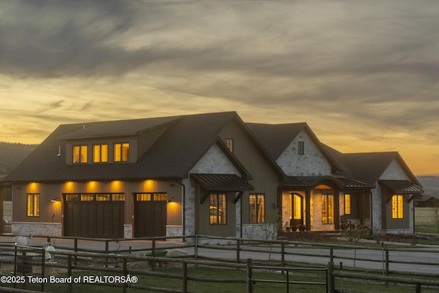 1070 Horseshoe Ln, Driggs, ID 83422 - view of front of property with stone siding, a standing seam roof, metal roof, a fenced front yard, and a garage