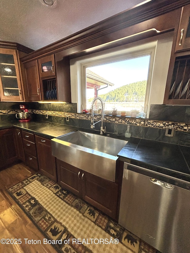 125 Wagon Rut Ln, Auburn, WY 83111 - kitchen featuring dishwasher, a sink, backsplash, glass insert cabinets, and a textured ceiling