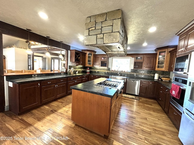125 Wagon Rut Ln, Auburn, WY 83111 - kitchen with stainless steel appliances, dark countertops, a peninsula, a textured ceiling, and a kitchen island