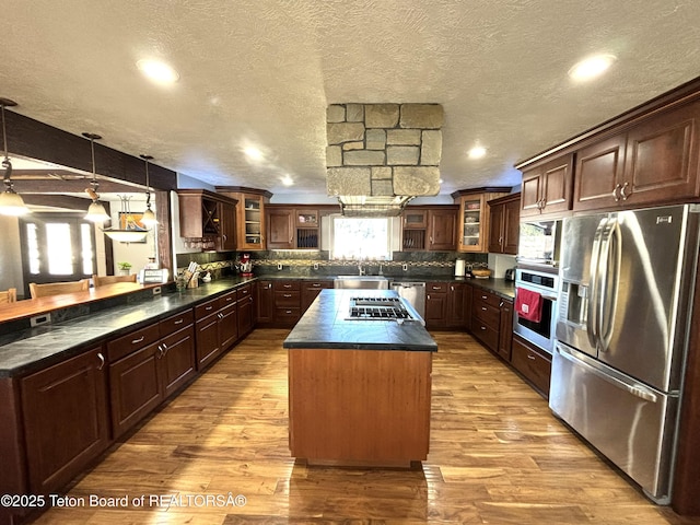 125 Wagon Rut Ln, Auburn, WY 83111 - kitchen with stainless steel appliances, dark countertops, a kitchen island, a sink, and a textured ceiling