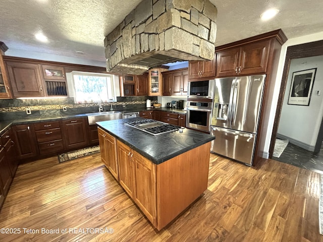 125 Wagon Rut Ln, Auburn, WY 83111 - kitchen with appliances with stainless steel finishes, a textured ceiling, dark countertops, light wood finished floors, and a sink