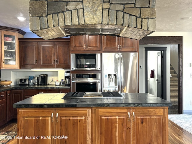 125 Wagon Rut Ln, Auburn, WY 83111 - kitchen with appliances with stainless steel finishes, dark wood-style floors, a kitchen island, glass insert cabinets, and a textured ceiling