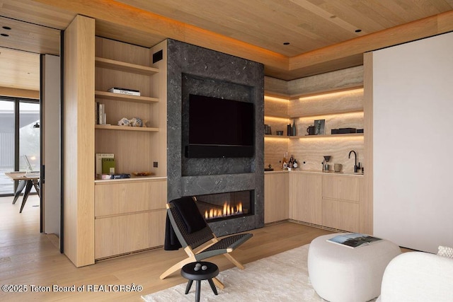 2205 W Pemmican Rd, Jackson, WY 83001 - living area with a tile fireplace, light wood-style floors, wooden ceiling, and built in features