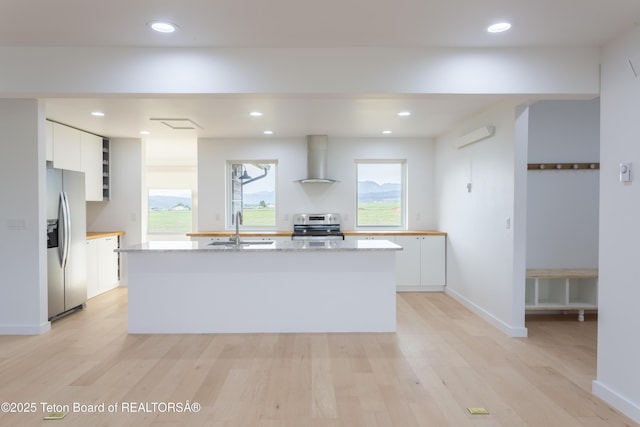 969 Caribou Peak Loop, Etna, WY 83118 - kitchen with wall chimney range hood, appliances with stainless steel finishes, white cabinets, light wood-style floors, and recessed lighting
