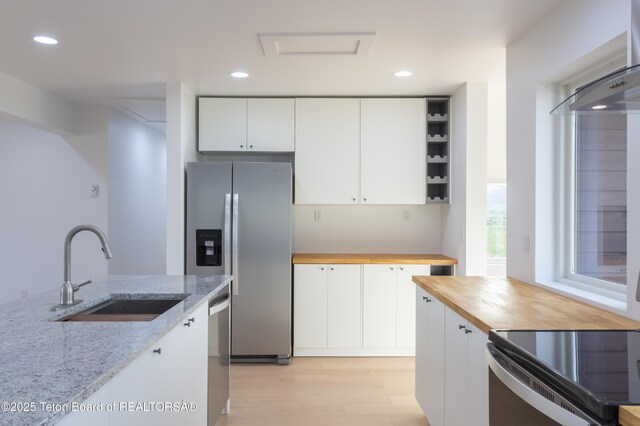 969 Caribou Peak Loop, Etna, WY 83118 - kitchen featuring appliances with stainless steel finishes, butcher block counters, open shelves, wall chimney range hood, and white cabinets