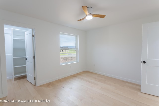 969 Caribou Peak Loop, Etna, WY 83118 - unfurnished bedroom with light wood-style flooring, a walk in closet, a closet, and ceiling fan