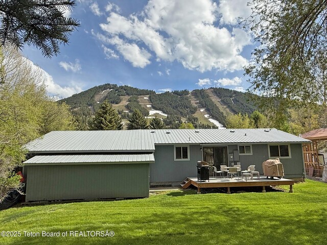 335 E Hansen Ave, Jackson, WY 83001 - back of property with a deck with mountain view, a yard, and metal roof