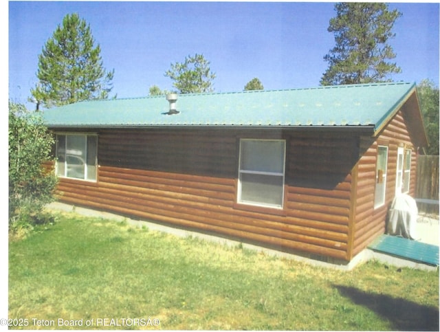 view of side of property featuring a lawn, metal roof, and log veneer siding