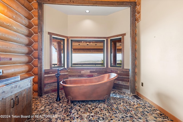 bathroom with a healthy amount of sunlight, a soaking tub, and rustic walls