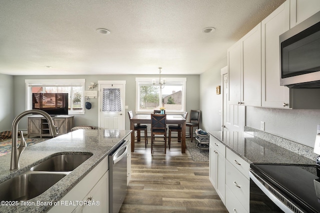 811 Jade St, Pinedale, WY 82941 - kitchen featuring stainless steel appliances, a sink, dark wood-type flooring, a chandelier, and white cabinets