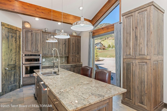 kitchen with stone tile flooring, appliances with stainless steel finishes, light stone countertops, and a sink