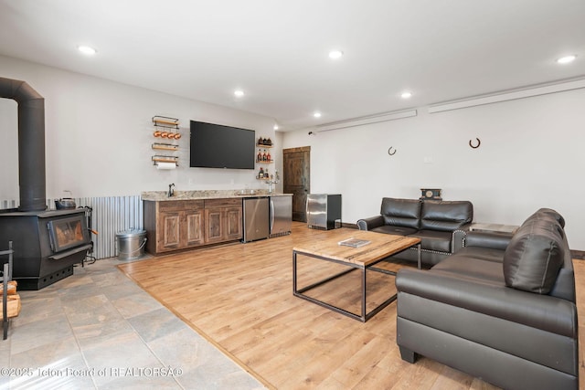 living room with a wood stove, indoor wet bar, and recessed lighting